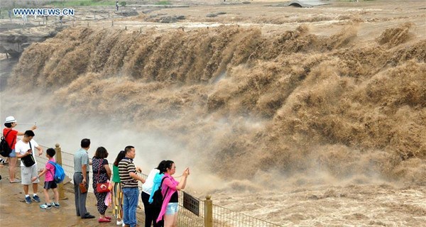Tourists watch Hukou Waterfall of Yellow River in N China 