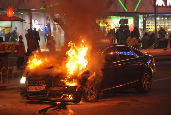 Flames rise from Wang Kes Audi on Beijings Donganmen Street on Dec 17 after allegedly being hit by a station wagon driven by Wang Shuo, who is now facing prosecution for possession of illegal we
