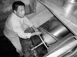 Wang Gangcheng is working by the solids and liquid separator. (Photo: Beijing Morning Post)