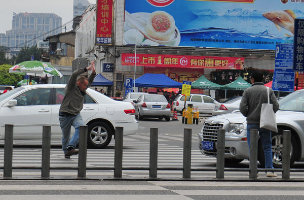 A Finnish foreign language teacher jumps into the road and uses tai chi to force cars to stop at a zebra crossing for pedestrians in Fuzhou.[Whats On Xiamen photo/CFP]