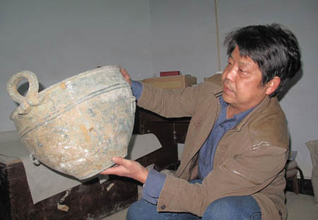 Yi Zelin checks a newly mended piece of bronze ware at his workshop in Xiangyang, Hubei province, in Central China on Nov 23.[Guo Rui / China Daily]