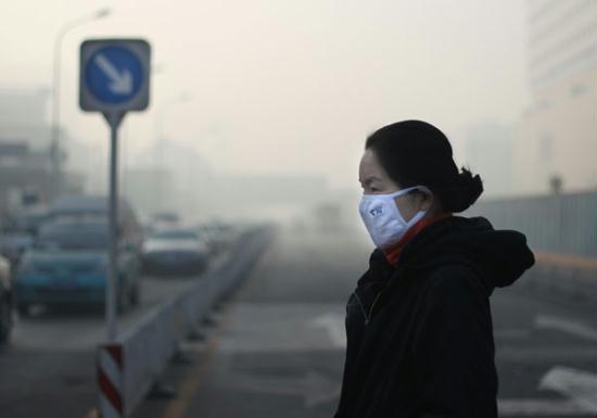 A resident wearing a mask and sunglasses walks in Beijing, as heavy smog hit the city on