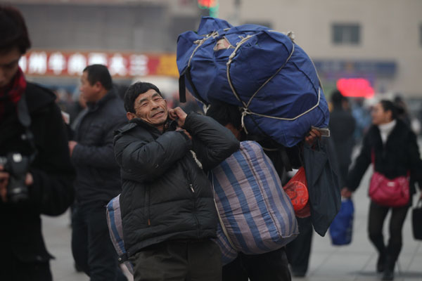 A migrant worker carries his baggage preparing to enter the Beijing Railway Station on Sunday. With the Spring Festival approaching, at least 400,000 passengers leave the capital every day. Wang Jing / China Daily 