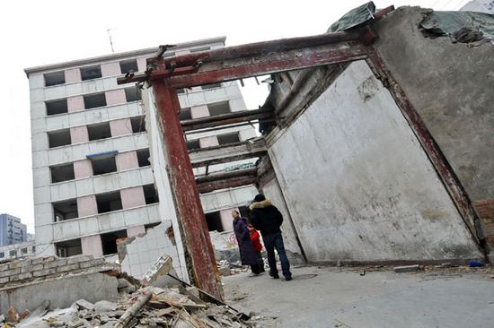 Liang's siheyuan, the traditional courtyard home, is demolished to piles of rubble surrounding a lone wooden gate.