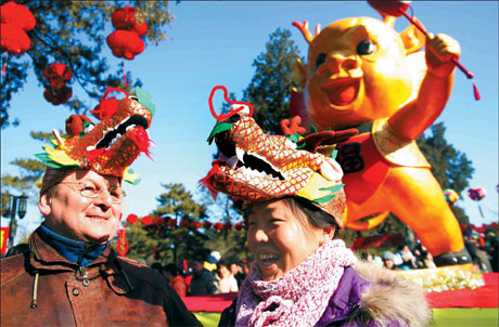 A foreign tourist and a local resident share a light moment at the Ditan Park Temple Fair in Beijing on Tuesday. Chen Xiaogen / For China Daily