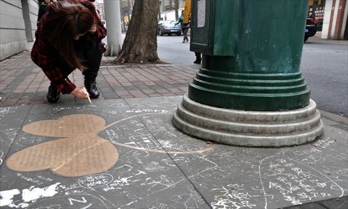 Next to a special postbox on Tian'ai Road, a woman uses a correction pen to write on the ground next to the Sweet Love wall in Hongkou district Sunday. [Photo: Cai Xianmin/GT]