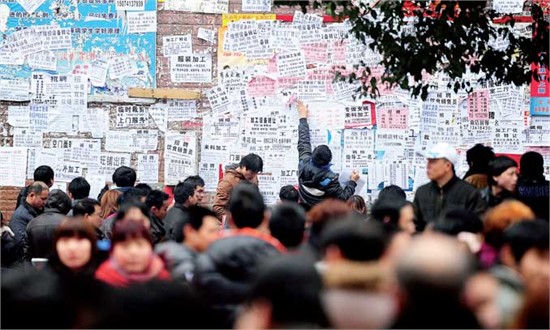 A man posts an employment notice on a billboard in a labor market in Zhuzhou, Hunan Province. Employers from local clothing factories have pledged to offer better pay and favorable working environments in a bid to alleviate the labor shortage amid complai
