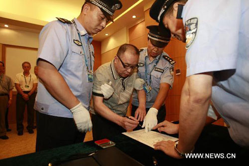 Alleged smuggling kingpin Lai Changxing (C) signs a warrant issued for his arrest as he arrives at the Beijing Capital International Airport in Beijing, capital of China, July 23, 2011. Lai, who is China's most-wanted smuggler, was repatriated back to China on Saturday after 12 years on the run, according to the Ministry of Public Security. Lai is accused of running a multibillion-dollar smuggling ring based in Xiamen, southeast China's Fujiang Province in the 1990s. [Photo: Xinhua/Zhang Jianxin]