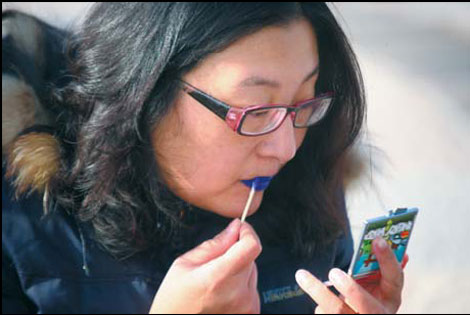 A woman who has pulmonary arterial hypertension, which leads to heart failure, applies blue lipstick to increase public awareness of the rare disease.
