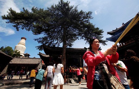 Tourists pray and burn incense at a temple in Wutai Mountain, one of China's four sacred Buddhist mountains, in Shanxi province. [Wei Liang / China News Service]