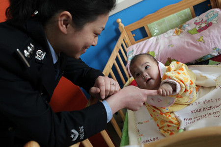 A police officer plays with a child rescued in an anti-human-trafficking campaign in Linyi, Shandong province, on Wednesday. [Zhang Zheng / for China Daily]