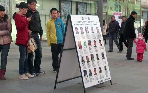 A signboard attracts the attention of passers-by in a market in Shenyang, Liaoning province, on Tuesday. The signboard, set up at the entrance of the market, shows 20 convicted thieves and lists their names, ages and criminal records as a warning to shopp