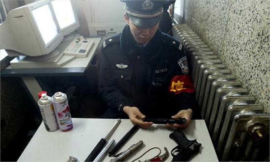 A police officer at Beijing Railway Station examines a replica gun, presented together with other confiscated objects banned by Chinese law, in 2009. Photo: CFP