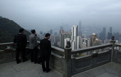 Visitors to The Peak, a tourist attraction, look at high-rise residential and commercial towers in Hong Kong. More and more wealthy mainlanders are buying property in the city. [Photo / Reuters]