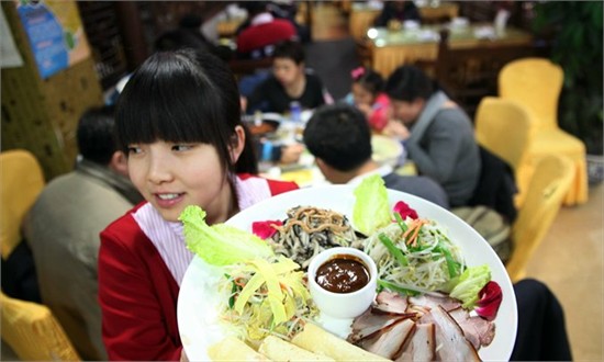A waitress serves a spring roll platter at Furunjia Shifu, Anhui Beili, Chaoyang district in February. [Photo: CFP]