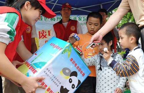 Children put used batteries into a recycling bin during an environmental protection campaign held in April 2011 in Meizhou city, Guangdong province. [Photo: Zhong Xiaofeng/China Daily]