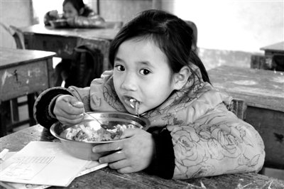 A schoolgirl is having lunch in Napo County on March 13, 2012. It was reported that some schools there were buying Zhuangzhuang Buffalo Milk for the Free Lunch program, and that suppliers earned 1 yuan from a subsidy of 3 yuan for each serving of the milk.