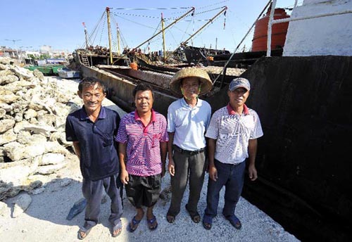 Fisherman Cheng Minghai (1st L), Li Liang (2nd L), Deng Yeping (2nd R) and Xu Detan (1st R) pose for photos in front of their fishing boat in Qionghai City, south China's Hainan Province, April 15, 2012. All 12 Chinese fishing vessels, which had sought refuge from bad weather at a lagoon off the Huangyan Island but were blocked the entrance of the lagoon by a warship of the Philippines on April 8, left the lagoon in Huangyan Island on Saturday after a five-day stalemate. One fishing boat has safely returned to Qionghai of south China's Hainan Province. (Xinhua/Guo Cheng)