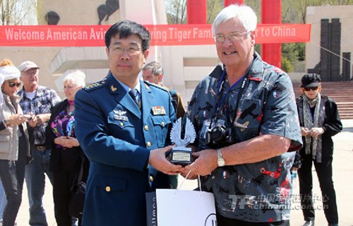 The photo shows that Larry, president of the American Flying Tigers History Committee, presents a souvenir to Qi Xiande, curator of the China Aviation Museum. (Photo by Cheng Yifeng)