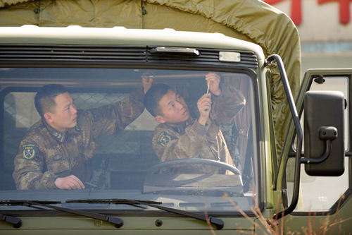 Li Hong (left), a squad leader in Lei Feng's Regiment, instructs a soldier in checking and repairing a truck in Fushun, Liaoning province, this month. Li Xin / Xinhua