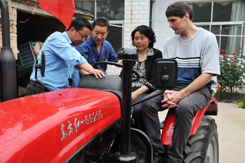 A technician (second left) explains how to operate a tractor to Chen Guihua (second right), her younger son Li Junwei (left) and David Bowers, an Australian working in China, at Chens home in Suiping, Henan Province, on Monday. Bowers donated the tracto