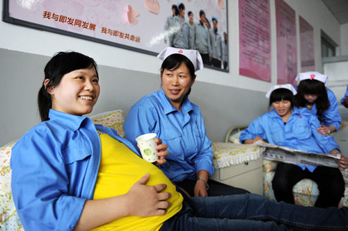 Song Qianqian, who is eight months pregnant, chats with one of her colleagues in a lounge specially designed for female workers in a textile company in Qingdao, East Chinas Shandong Province, in April. [Photo: Li Ziheng / Xinhua]