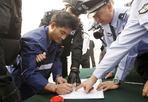 Naw Kham, a drug lord suspected of masterminding the murder of 13 Chinese sailors on the Mekong River last year, signs on the arrest warrant in Beijing, capital of China, May 10, 2012. [Photo/Xinhua]