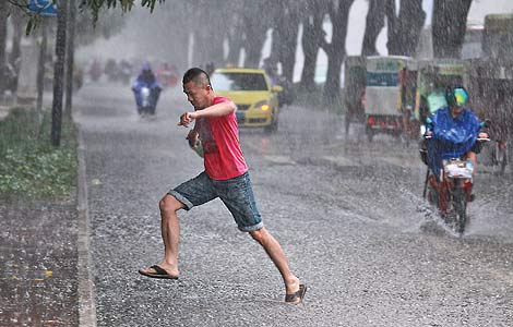 A man crosses a flooded street in heavy rain in Nanning, the Guangxi Zhuang Autonomous Region, on Monday. [Photo: Tang Huiji / China Daily]