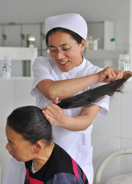 A nurse combs the hair of a new patient at the Mental Health Center of Zouping, Shandong Province, on Friday. Dong Naide / China Daily 