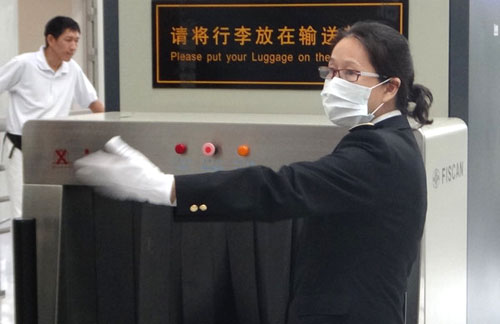 Ye Sui, an officer responsible for anti-drug trafficking at Shenzhen Bao'an International Airport, guides passengers for luggage checks. Huang Yuli / China Daily
