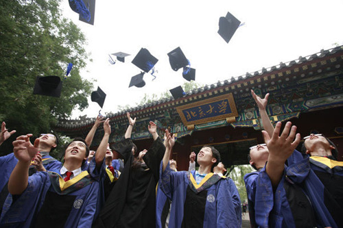 Graduates throw their caps into the air to celebrate graduation at the west gate of Peking University last year. Ren Zhenglai / Xinhua