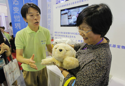 A worker from a Japanese company shows visitors a therapeutic robot seal named Paro, which is used to provide a companion to the elderly. The 2012 China Forum on the Development of the Senior Service Industry opened in Shanghai on Thursday.[China Daily]