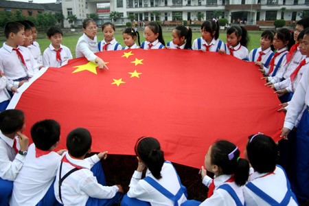 A Chinese primary school teacher explains to her students about information of the Chinese national flag at a ceremony marking the first day of the new semester in the city of Hanshan in east China's Anhui Province, September 1, 2009. [File photo: Xinhua]