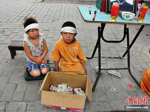 The photo, taken on May 28, 2012, shows the boy and his sister take to the streets to beg for money for their fathers burial [Zhang Yuan / Chinanews.com]