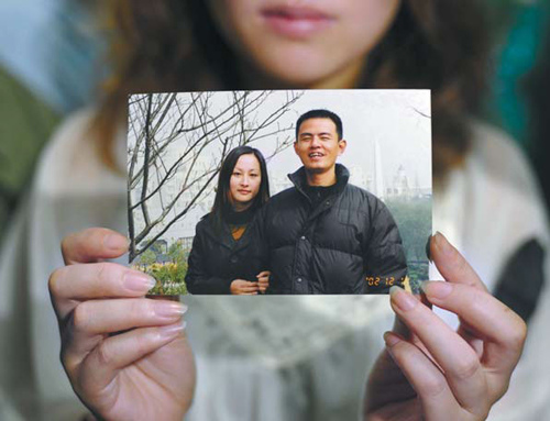Wang's sister, Wang Limin, holds a photo of Wu and his wife. [China Daily]