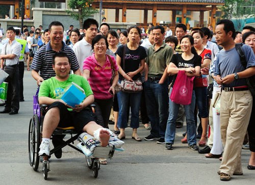 Parents of Chai Zixin push their son's wheelchair into the national college entrance examination site at Yucai Middle School in Xi'an, capital of Northwest China's Shaanxi province, on Thursday. Chai broke his leg about 10 days before the exam. Yuan Jingzhi / for China Daily.