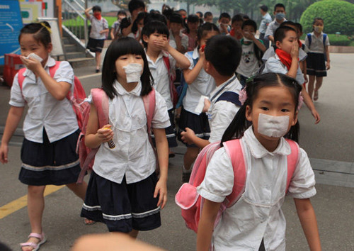 Students at the Yucai Primary School in Wuhan, capital of Hubei province, on Monday cover their mouths with pieces of cloth to prevent themselves from inhaling smog caused by straw burning. Jin Siliu / for China Daily