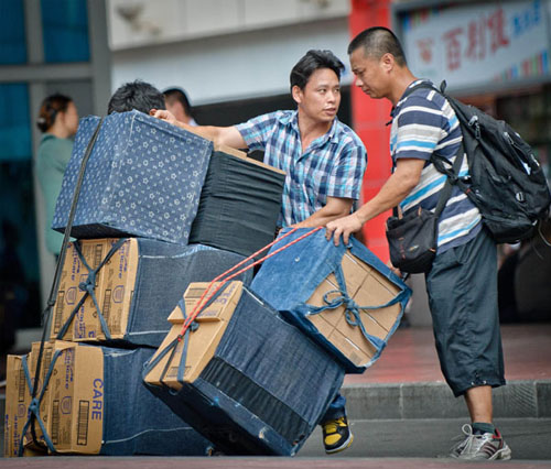 Two men take care of boxes containing foreign milk powder products brought from Hong Kong outside the Luohu Port in Shenzhen, Guangdong province, on May 24. Liu Dawei / Xinhua 