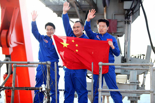 Chinese oceanauts wave hands after the submersible Jiaolong returns from 7,020 meters beneath the sea on June 24, 2012. [Photo/Xinhua]