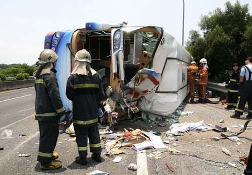 Rescuers stand next to a bus, which carried tourists from Harbin, Heilongjiang province, and rolled over on a highway in Hsinchu city, Taiwan, on Saturday. [Photo/Agencies]