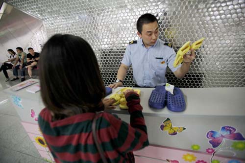 In Beijing's Xi'erqi subway station, a staff worker tidies up slippers offered to passengers who have lost their footwear among the crowd. Kuang Linhua / for China Daily