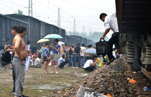 Passengers take a rest after getting off a train in Ningling county, Henan province, on Sunday, because of a sudden rain. The train, bound for Hefei, Anhui province, was delayed for about eight hours. Ren Hongbing / for China Daily