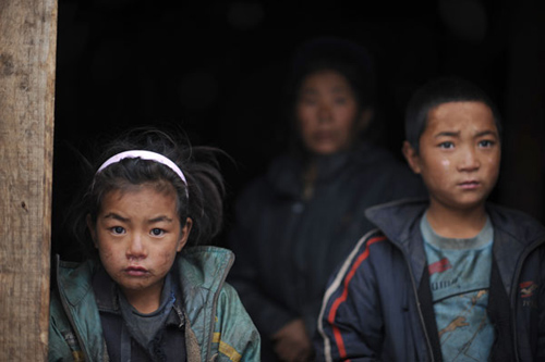 Mezuo, left, and her 9-year-old brother, Meka, right, live with their aunt, in background, who has mental disorder, in the Liangshan Yi autonomous prefecture of Sichuan province. Provided to China Daily