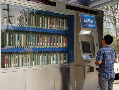 A self-service library attracts a passer-by's attention in Beijing recently. Containing more than 400 books, it allows users to borrow and return books 24-hours a day. [Photo: China News Service]  