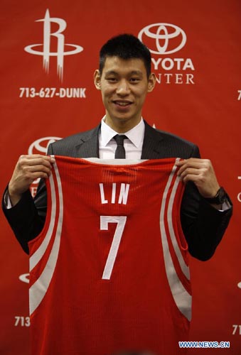 Jeremy Lin poses with his jersey during a news conference after signing a deal to play for the Rockets, in Houston July 19, 2012. (Xinhua/ Song Qiong)