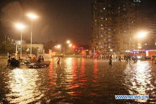 Firefighters pull a submerged car near Guangqumen Bridge in Beijing, capital of China, July 21, 2012. Beijing received 117 mm of precipitation on average as of 8 p.m., with a township in the suburban Mentougou district hit by the largest of 345 mm, accord