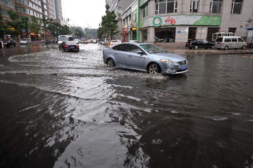 A car runs on a flooded road in Taiyuan, capital of north China's Shanxi Province, July 31, 2012. A downpour hit the city on Tuesday morning and the provincial meteorological center has issued a red alert for thunderstorms. (Xinhua/Zhan Yan) 