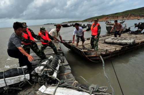 Border guards help fishermen secure their boats at a port in Fuqing, Fujian province, on Tuesday. Tropical storm Saola is expected to hit Fujian and Zhejiang provinces on Thursday or Friday.
