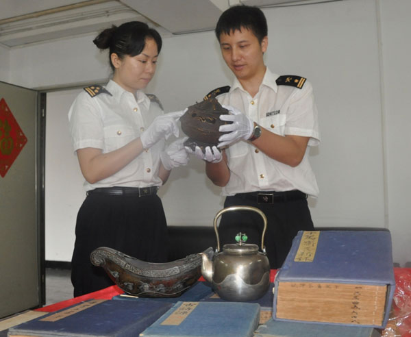 Customs officers examine the cultural relics they seized from a Japanese man at Huanggang Port in Shenzhen, Guangdong province, on Tuesday.