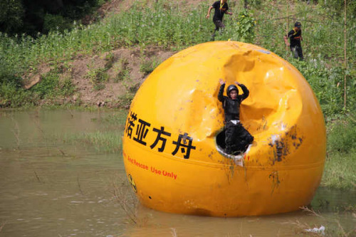 Yang Zongfu climbs out of his disaster-proof Noah's Ark safely after the device tumbled down a hillside into water in Yiwu county, East China's Zhejiang province, Aug 6, 2012.